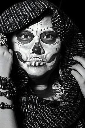 Black and white portrait with intricate skull face paint, capturing a dramatic Halloween theme.